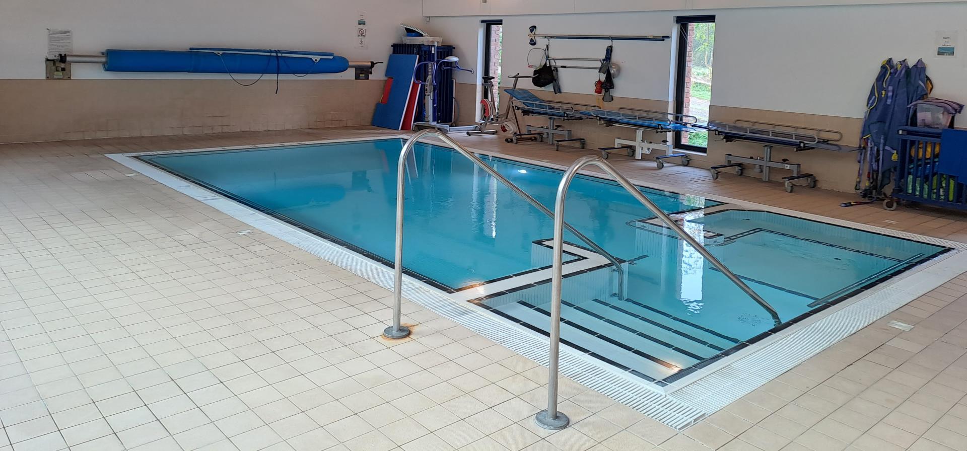 An indoor pool with a metal railing