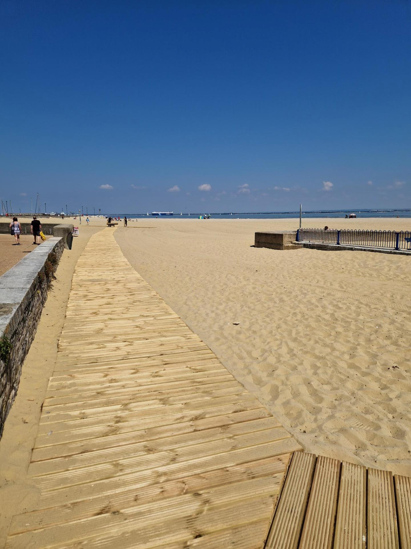 A wide wooden boardwalk extending over the sandy beach at Ryde's Harbour Beach on the Isle of Wight. 
The image doesn't show the added blue edging lines on either side of the boardwalk planks.