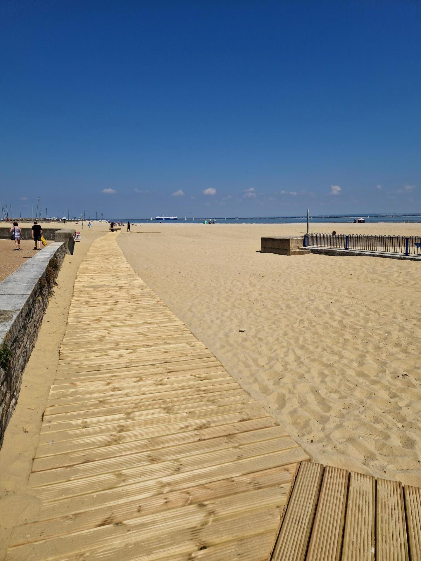 A wide wooden boardwalk extending over the sandy beach at Ryde's Harbour Beach on the Isle of Wight.