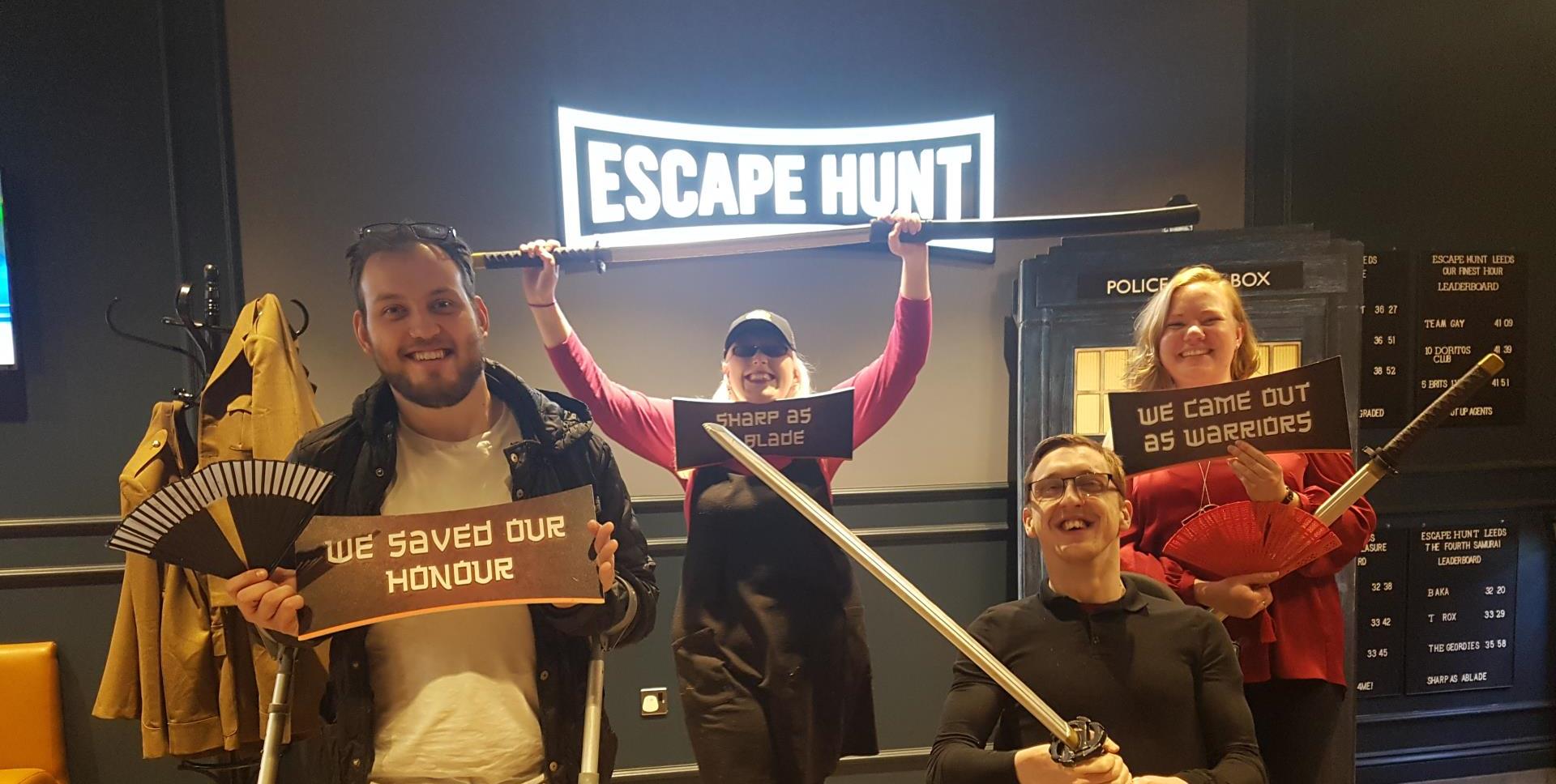 Victorious we have a team picture holding swords under the Escape Hunt logo